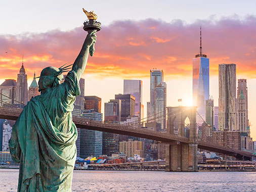 Statue de la Liberté et la silhouette urbaine de la ville de New York au crépuscule.