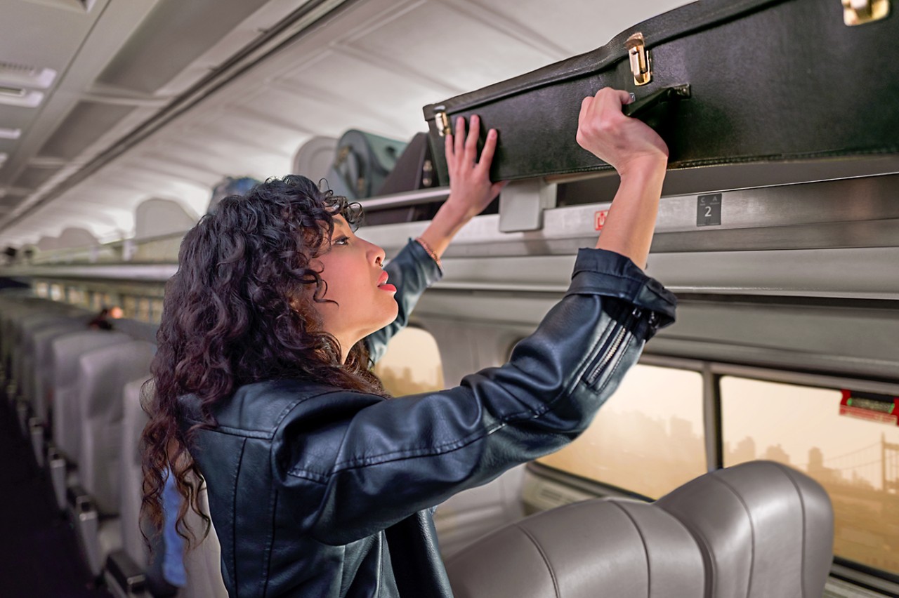 Woman Placing Baggage Overhead